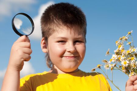 Boy sees flowers through magnifying glassの写真素材