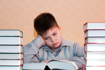 Tired kid with a stack of booksの写真素材