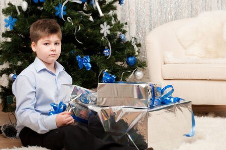 Boy with gifts near a Christmas treeの写真素材