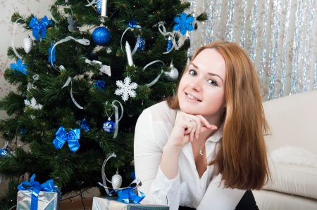 A young woman with gifts near a Christmas treeの写真素材