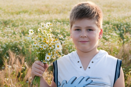 A boy with a bouquet of daisies in a fieldの写真素材