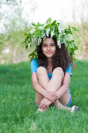 Teen girl with a wreath of cherry blossoms on her headの写真素材