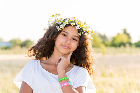 Teen girl with a wreath of daisies in  a fieldの写真素材
