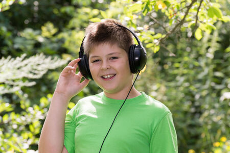 boy listening to music with headphones in the parkの写真素材