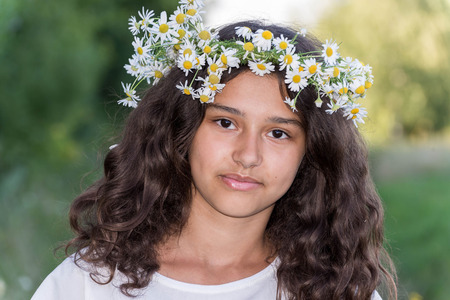 A teenage girl with a wreath of daisies on the natureの写真素材