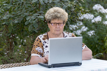 elderly woman working on  a computer in the garden