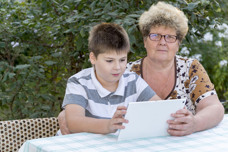 Granny with a grandson watching tablet in natureの写真素材