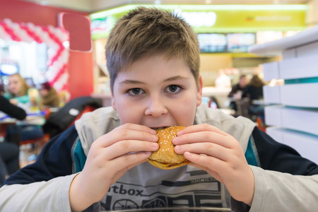 Teen boy eats a hamburger n Cafeの写真素材
