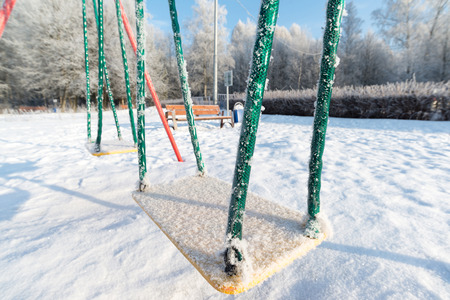 snow covered swing and slide at a playground in winterの写真素材