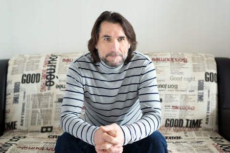 sad man sitting on a sofa in the roomの写真素材