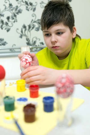boy paints the Easter eggs with  brushの写真素材