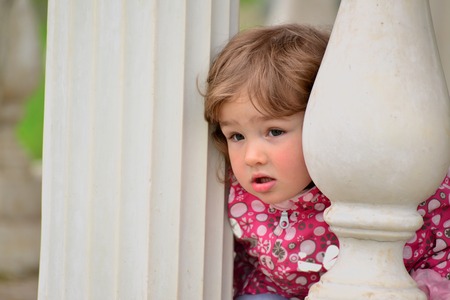 Two year old girl looks out from the gazebo