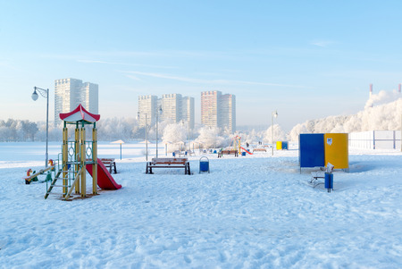 snow covered swing and slide at playground in a winterの写真素材
