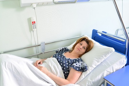 Female patient lying on a bed in hospital wardの写真素材