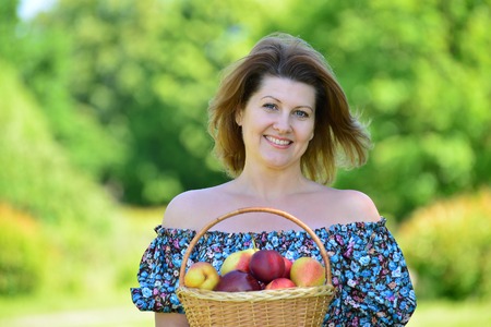 An adult woman with a basket of fruit in the parkの写真素材