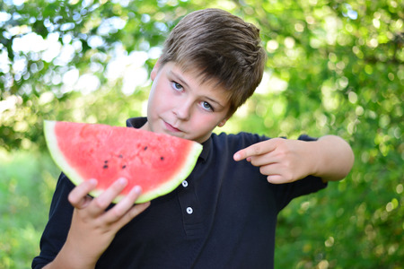 Teen boy eating watermelon in a natureの写真素材