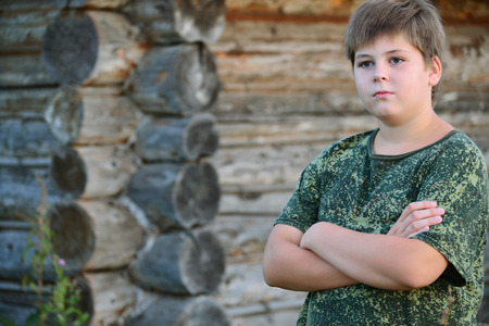 Teen Boy in camouflage stands near a wooden wallの写真素材