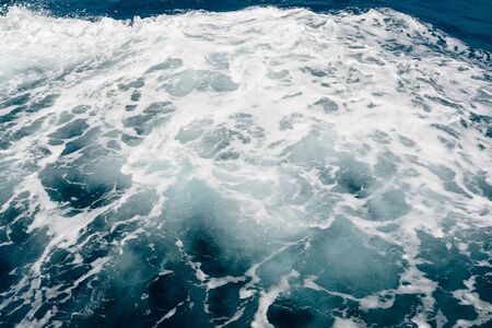 white foam on the surface of the blue sea waterの写真素材