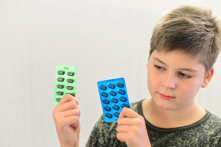 Boy in camouflage shirt holding a drugの写真素材