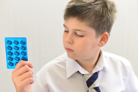 A teenage boy with the medicine in his handsの写真素材