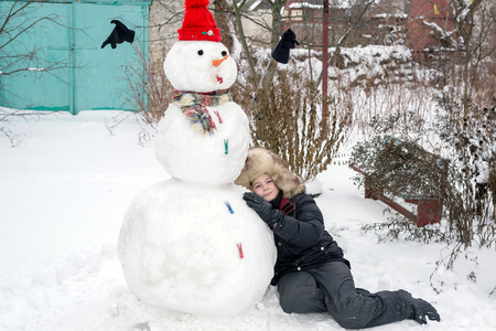The boy in a fur hat near snowmanの写真素材