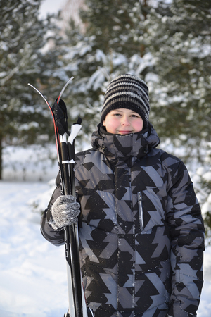 Teen Boy with skis in a pine forest in winterの写真素材