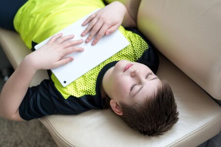 Boy playing on the tablet while lying on the couch