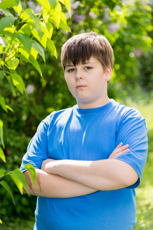 The boy crossed his arms in a summer parkの写真素材