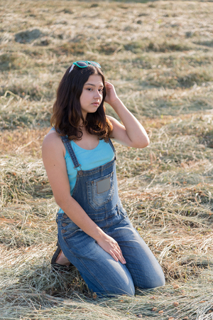Beautiful teen girl in a field with strawの写真素材