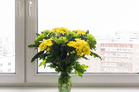 Bouquet of yellow chrysanthemums and green stands on the windowsillの写真素材