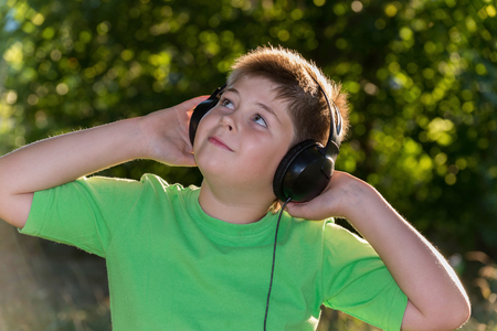 Cheerful boy listening to music with headphones in parkの写真素材