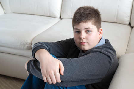 13 year boy sitting near the sofa in the roomの写真素材