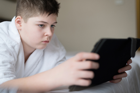 Boy in bathrobe Uses a tablet in hotel roomの写真素材