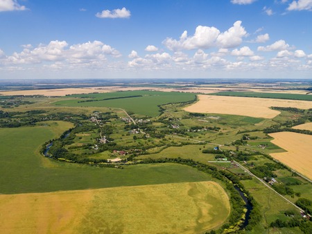 A view from the air to the village, surrounded by fields and a riverの写真素材