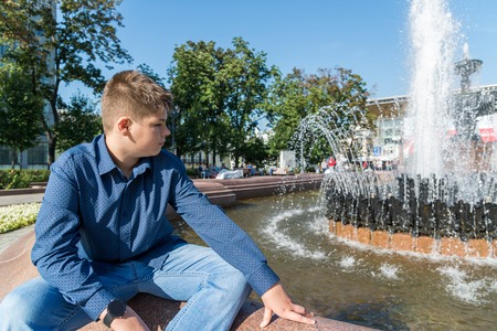 Teenager of 14 years is sitting near fountainの写真素材