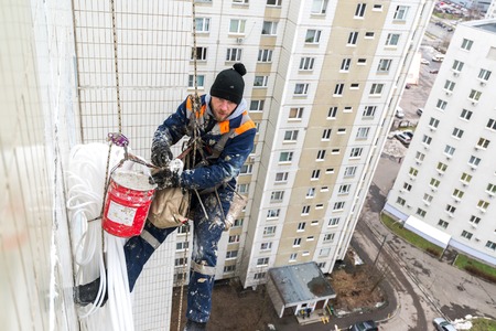 Moscow, Russia - December 18. 2018. Mountaineer employee of public services warms the facade of...