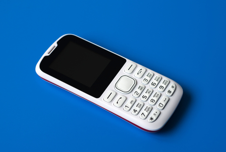 White cell phone with buttons on a blue background.の写真素材