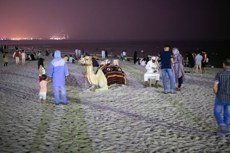 Ajman, UAE - April 6. 2018. Locals relax from heat on a public beach at night. Tradition