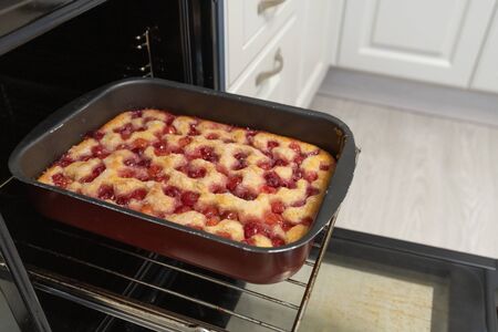 Baked cherry pie on baking sheet in the ovenの写真素材
