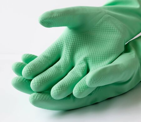 Green latex dishwashing gloves on white backgroundの写真素材