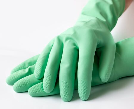 Green latex dishwashing gloves on white backgroundの写真素材