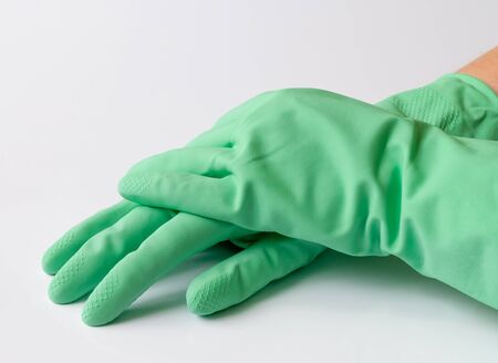 Hand in green latex dishwashing gloves on a white backgroundの写真素材