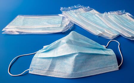 Used disposable and new in packaging medical mask on blue backgroundの写真素材