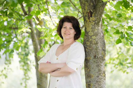 Russian woman with phone near the birch in the summerの写真素材