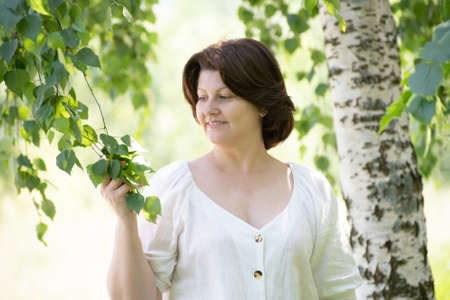 brunette woman near tree in summer parkの写真素材