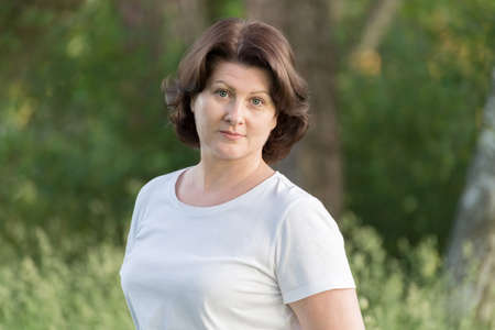 brunette woman near tree in summer parkの写真素材