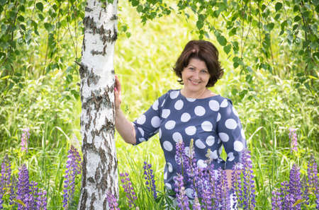 Russian woman near the birch in the summerの写真素材