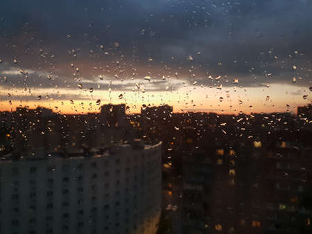 View of sunset in the city through glass wet from rainの写真素材