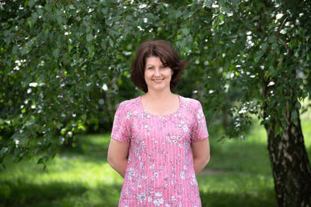 Woman in a pink dress on a summer forest backgroundの写真素材