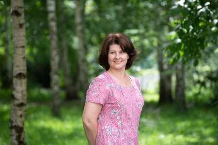 Woman in a pink dress on a summer forest backgroundの写真素材